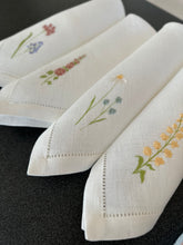 Ielādēt attēlu galerijas skatītājā, white linen napkins with machine‑embroidered meadow wildflowers motifs and hemstitched edges