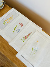 Ielādēt attēlu galerijas skatītājā, white linen placemats with machine‑embroidered meadow wildflowers motifs and hemstitched edges - perfect eco table linens for botanical dining; hostess gifts.