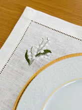 Load image into Gallery viewer, Bring quiet, botanical elegance to your table with these linen place mats embroidered with lily of the valley. Made from natural European linen, they protect surfaces beautifully while adding a refined spring-floral detail. Perfect for coffee moments, hosting, and thoughtful gifting.