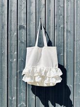 Load image into Gallery viewer, White linen tote bag with romantic ruffle detail, handmade linen shopper bag hanging on a grey wooden wall