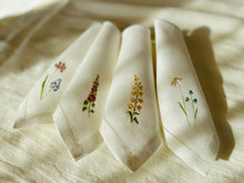Ielādēt attēlu galerijas skatītājā, white linen napkins with machine‑embroidered meadow wildflowers motifs and hemstitched edges
