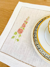 Ielādēt attēlu galerijas skatītājā, white linen placemats with machine‑embroidered meadow wildflowers motifs and hemstitched edges - perfect eco table linens for botanical dining; hostess gifts.
