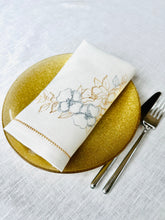 Ielādēt attēlu galerijas skatītājā, Off white linen dinner napkins with gold and silver floral embroidery and hemstitch edge on elegant table setting
