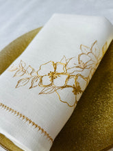 Ielādēt attēlu galerijas skatītājā, Piena baltas lina salvetes ar zelta un sudraba ziedu izšuvumu un ažūra maliņu uz eleganti klāta galda
