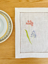 Ielādēt attēlu galerijas skatītājā, white linen placemats with machine‑embroidered meadow wildflowers motifs and hemstitched edges - perfect eco table linens for botanical dining; hostess gifts.
