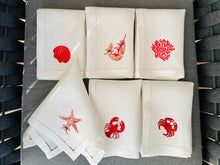 Ielādēt attēlu galerijas skatītājā, Set of white napkins with red embroidered designs on a textured surface. A beautiful and thoughtful choice for anyone who loves coastal living, seafood dinners, and naturally elegant table settings.
